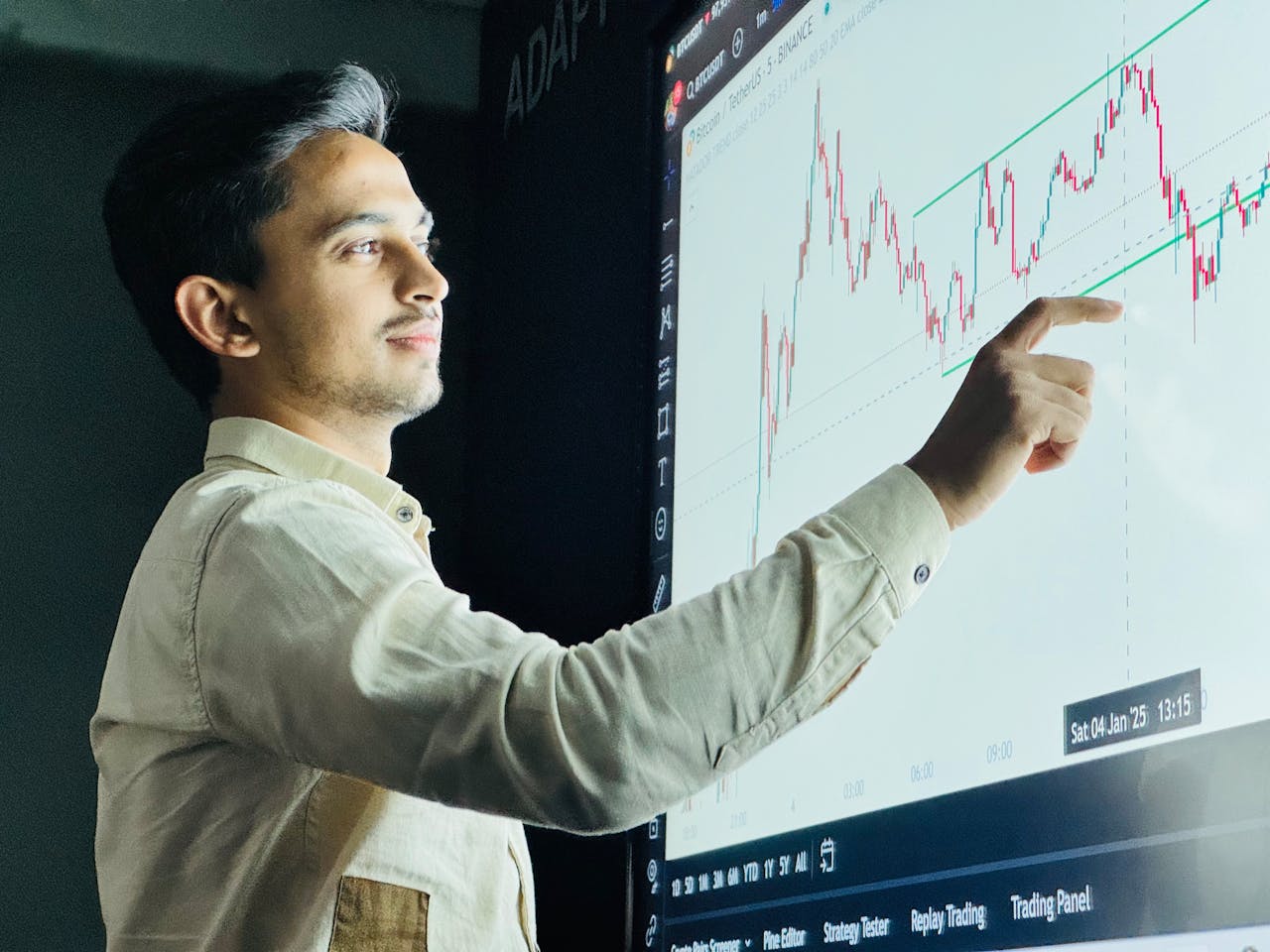 about-us-02 Man analyzing stock market graph on a digital board with a focused expression.