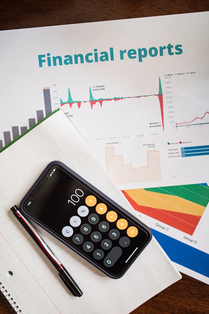 services-01 Top view of financial reports with a calculator app open on a smartphone.